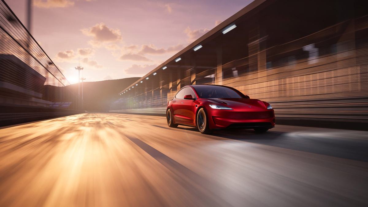 Red Tesla Model 3 on the road at sunset