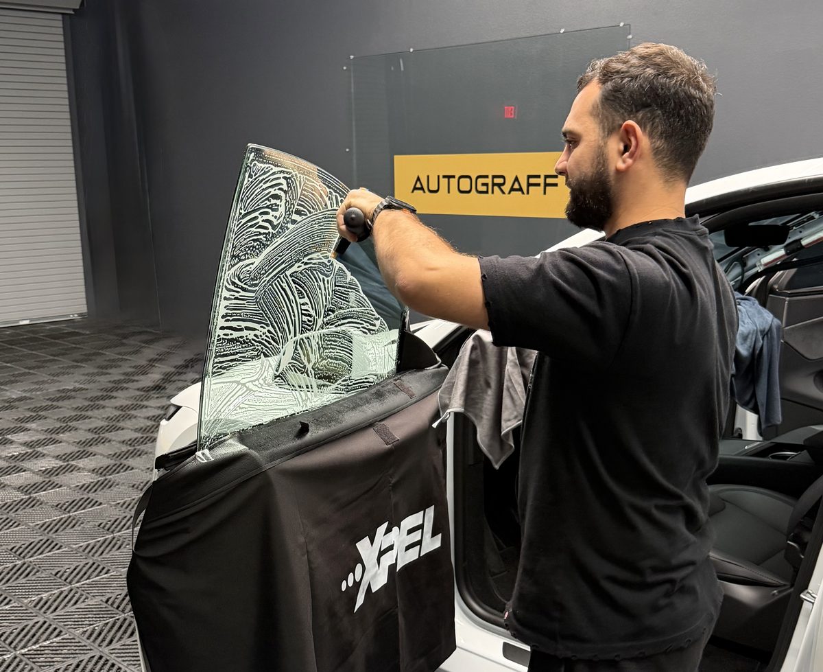 Installer fitting XPEL window film on a Tesla door at Autograff