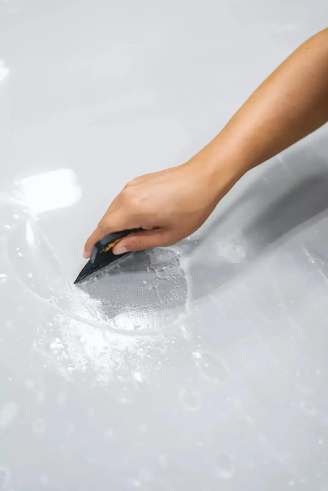 Installer squeegeeing XPEL paint protection film on a white car